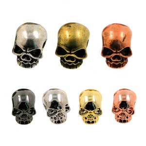 May include: Six skull-shaped beads in different metal finishes: silver, gold, copper, black, nickel, and rose gold. These beads are perfect for jewelry making, crafts, and DIY projects.