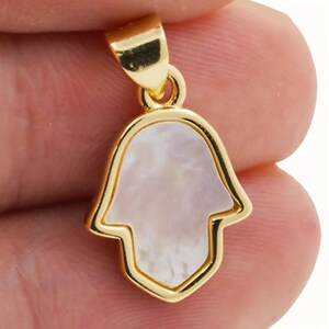 May include: Gold-tone pendant featuring a white mother-of-pearl hamsa hand charm.