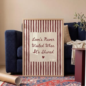 Puede incluir: Impresión artística enmarcada con el texto "Love's Never Wasted When It's Shared". La impresión tiene un fondo crema con rayas burdeos y un pequeño corazón. El marco es de madera clara. Ideal para decoración.