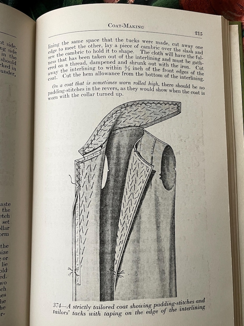 Puede incluir: Una p&aacute;gina de un libro titulada Coat-Making, p&aacute;gina 215, que presenta un dibujo lineal en blanco y negro etiquetado 374-A strictly tailored coat showing padding-stitches and tailors' tacks with taping on the edge of the interlining, con instrucciones.