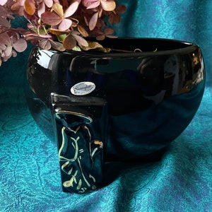 May include: Black ceramic planter with a gold-painted figure on the side. The planter has a label that reads "Shanghai".