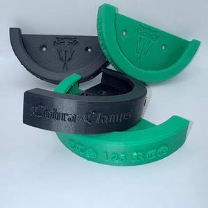 May include: A collection of 3D-printed Cobra Clamps in black and green. The black clamps feature a snake logo and the text "Cobra-Clamps". The green clamps have the same snake logo and the text "CTS 125 RCG".