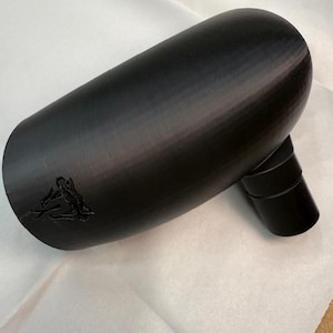 May include: A black, cylindrical object with a curved body and a smaller, angled spout. The object has a textured surface and a small, embossed design near the opening. The item is likely a component or accessory.