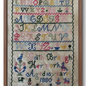 May include: A framed sampler with the alphabet embroidered in colorful thread. The sampler also includes the text "Edith Brough Her work 1880".