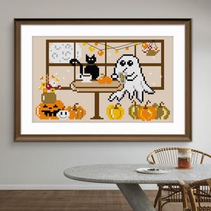 May include: A framed cross-stitch pattern featuring a pixelated white ghost and a black cat sitting at a table with mugs. The scene includes orange pumpkins, a jack-o'-lantern, a small smiley face, and a vase of flowers, all set against a window.