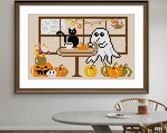May include: A framed cross-stitch pattern featuring a pixelated white ghost and a black cat sitting at a table with mugs. The scene includes orange pumpkins, a jack-o'-lantern, a small smiley face, and a vase of flowers, all set against a window.