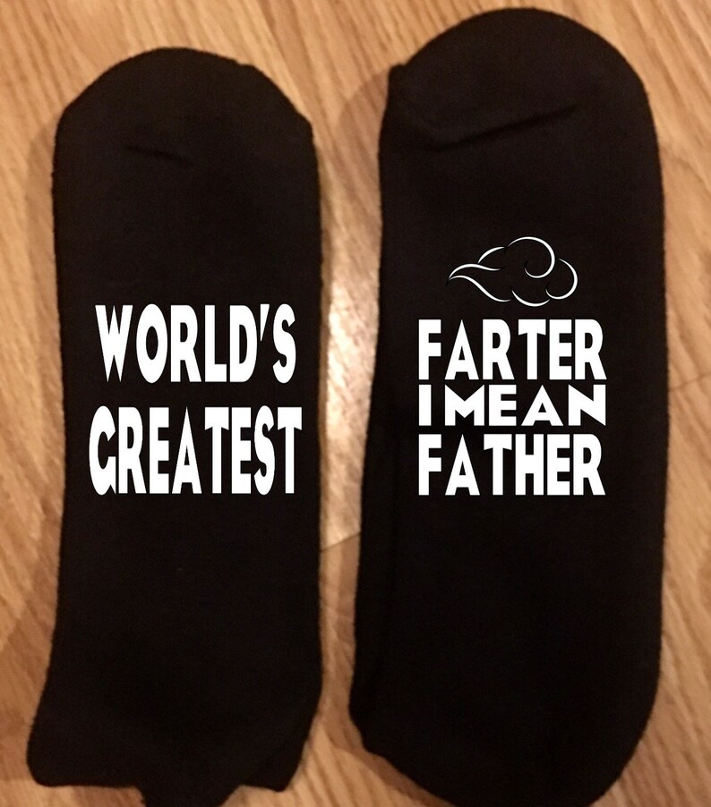 May include: Two black socks with white text. One sock reads "WORLD'S GREATEST". The other sock reads "FARTER I MEAN FATHER" with a cloud graphic above the text.