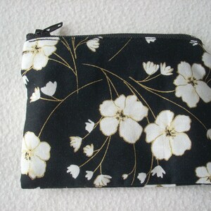 Monedero de algodón negro con estampado de flores blancas con contornos dorados. Bolsa pequeña.
