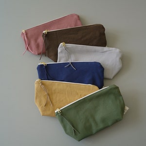 May include: Six zippered pouches in a variety of colours, including pink, brown, grey, blue, yellow, and green. The pouches are made from a soft, canvas-like material and have a zipper fastening.