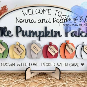 Peut inclure: Panneau en bois avec l'inscription "Bienvenue chez Nonna et Pop's Little Pumpkin Patch". Le panneau présente six citrouilles colorées, chacune avec une étiquette nominative. Le panneau est soutenu par un support en bois.