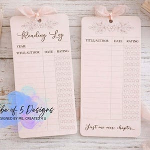 May include: Two pink reading log bookmarks with floral accents and attached ribbons. One bookmark reads "Reading Log" and includes spaces for title, author, date, and rating. The other says "Just one more chapter..."