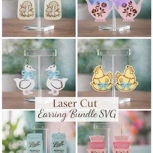 Pode incluir: Uma coleção de brincos cortados a laser exibidos em suportes transparentes. Os designs incluem potes de cogumelos, bules com detalhes florais, patos com laços azuis, galinhas com laços azuis, potes Ball e tigelas rosa empilhadas.