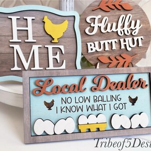 Puede incluir: Tres letreros de madera con tem&aacute;tica de granja. El primer letrero dice "Home Me" con una silueta de pollo amarilla. El segundo letrero dice "Fluffy Butt Hut" con hojas marrones. El tercer letrero dice "Local Dealer No Low Balling I Know What I Got" con una silueta de pollo marr&oacute;n, una caja de huevos amarilla y huevos blancos.