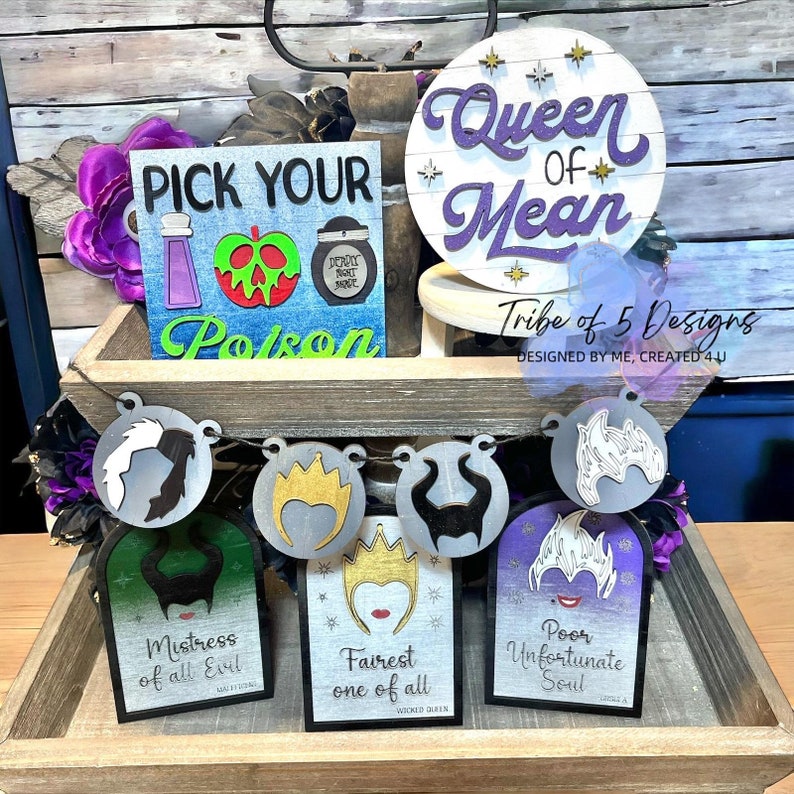 May include: A set of five wooden signs featuring Disney Villains. The signs are decorated with images of Maleficent, the Evil Queen, Ursula, and Cruella de Vil. The signs are painted in black, white, and purple. The text on the signs reads "Mistress of all Evil", "Fairest one of all", "Poor Unfortunate Soul", and "Queen of Mean".