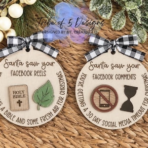 May include: Two round wooden ornaments with black and white buffalo plaid bows. The left ornament reads Santa saw your Facebook reels, you're getting a bible and some fresh air for Christmas, featuring a wooden bible and green leaf icon.