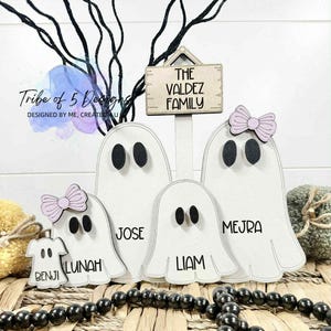 May include: A wooden family sign featuring ghost-shaped figures with names and a sign that reads "THE VALDEZ FAMILY." The ghosts are white with black oval eyes and some have pink bows. The names Benji, Lunah, Jose, Liam, and Mejra are printed on the ghosts.