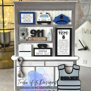 May include: A gray wooden shelf with police-themed decorations. Includes a police car, badge, hat, and the text "Serve Protect Honor." Also features a bulletproof vest and the text "Tribe of 5 Designs."