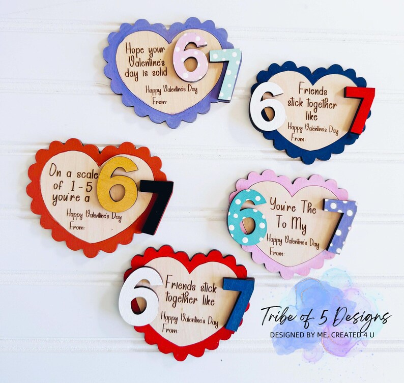 May include: Wooden heart-shaped Valentine's Day decorations with scalloped edges. Each heart features the numbers 6 and 7, with various colors and patterns. Text includes phrases like "Hope your Valentine's day is solid" and "Friends stick together like."