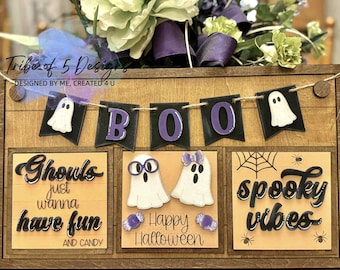 May include: Wooden Halloween decoration with a "BOO" banner and three panels. The panels read "Ghouls just wanna have fun," "Happy Halloween," and "spooky vibes." Features ghost and spiderweb designs.