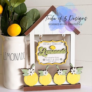 May include: A wooden sign with a white background and a brown roof. The sign says "Freshly Squeezed Lemonade" in yellow and green letters. The sign also says "Old Fashioned Recipe Sweet & Cold Made with Love". There are four yellow lemons with green leaves and white flowers on the bottom of the sign.