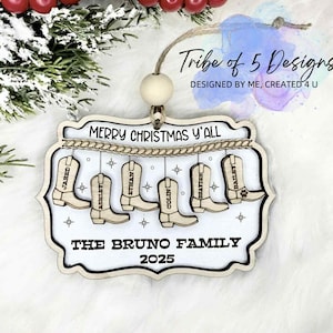 May include: Wooden Christmas ornament with the text "Merry Christmas Y'all" and "The Bruno Family 2025." The ornament features six cowboy boots with names. The ornament is hanging from a string with a wooden bead.