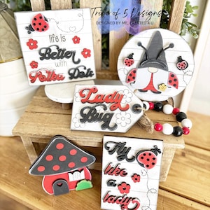 May include: A set of five wooden signs with ladybug and floral designs. The signs feature phrases like "Life is Better with Polka Dots" and "Fly Like a Lady".