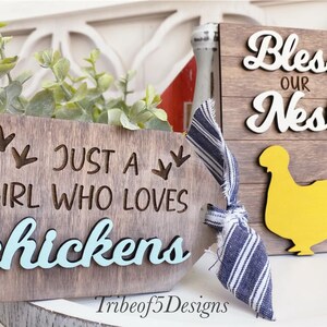 Puede incluir: Dos letreros de madera con tem&aacute;tica de granja. El primer letrero dice "Just a girl who loves chickens" con la palabra "chickens" pintada de azul y una silueta de una pata de pollo. El segundo letrero dice "Bless our nest" con la palabra "nest" pintada de blanco y una silueta de pollo amarilla.