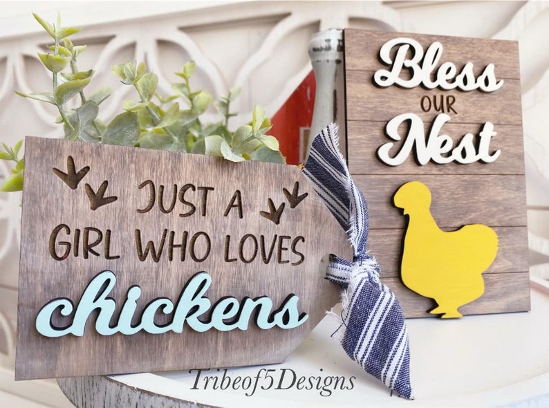 Puede incluir: Dos letreros de madera con tem&aacute;tica de granja. El primer letrero dice "Just a girl who loves chickens" con la palabra "chickens" pintada de azul y una silueta de una pata de pollo. El segundo letrero dice "Bless our nest" con la palabra "nest" pintada de blanco y una silueta de pollo amarilla.