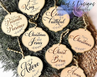 May include: Set of 5 wooden Christmas ornaments with various religious messages. The ornaments are beige with brown lettering and feature a rustic design. The messages include "Glory to the newborn King", "It's not about the presents, it's about his presence", "Christmas is about Jesus", "Come all ye faithful", "Christ is born", "Merry Christmas", "Let us adore him", and "Away in a manger".