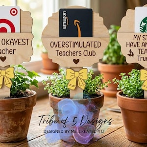 Puede incluir: Tres peque&ntilde;as plantas en macetas con letreros de madera. Los letreros dicen "World's OKAYEST Teacher", "OVERSTIMULATED Teachers Club" y "MY STUDENTS HAVE AN AWESOME TEACHER... True Story". Cada letrero contiene una tarjeta de regalo.
