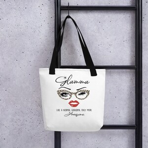 May include: White tote bag with black straps featuring a graphic of a woman's face with leopard print glasses and red lips. The text "*Glamma* Like a normal grandma only more *Awesome." is printed below the graphic.