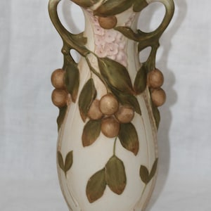 May include: Cream ceramic vase with two handles, decorated with brown fruit and green leaves. The vase has a pink floral design and is about 30 cm tall, suitable for home decor.