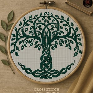 May include: A cross-stitch pattern of a tree with intertwined roots and branches, displayed in a wooden embroidery hoop. The tree design is in dark green thread against a light background. The text "CROSS STITCH PATTERN PDF" is at the bottom.