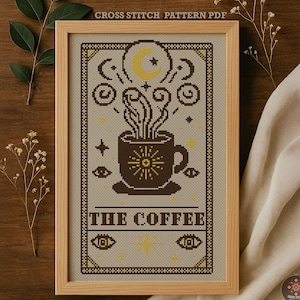 Może przedstawiać: Oprawiony wzór haftu krzyżykowego przedstawiający brązowy kubek kawy z motywem promieni słonecznych, parą i napisem "THE COFFEE". Projekt zawiera półksiężyc, gwiazdy i dekoracyjne obramowania w odcieniach brązu i żółci. U góry znajduje się napis "CROSS STITCH PATTERN PDF".
