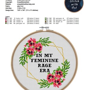 May include: A cross-stitch embroidery hoop with the text "IN MY FEMININE RAGE ERA" surrounded by pink flowers and green leaves. The design area is 7.93" x 7.93". The text "Cross Stitch with Art" is also visible.