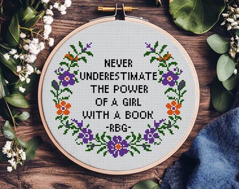 Può includere: Un modello a punto croce in un telaio di legno con la citazione "Never underestimate the power of a girl with a book -RBG-". Il design floreale presenta fiori viola e arancioni. Il testo "Cross Stitch Pattern PDF" è in basso.