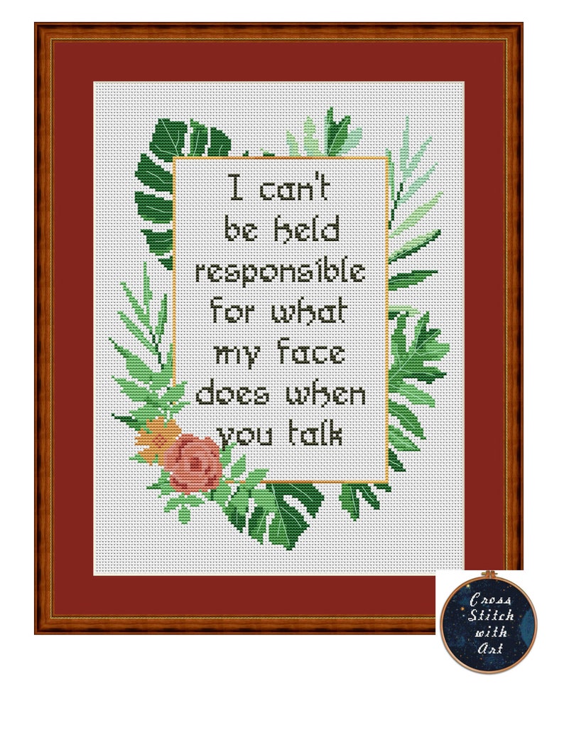 May include: Cross-stitch art framed in a brown wooden frame. The cross-stitch features the text "I can't be held responsible for what my face does when you talk" surrounded by green leaves and a pink flower. A small circular logo is in the bottom right corner.
