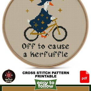 May include: A cross-stitch design in a wooden hoop features a goose in a witch hat and cloak riding a bicycle. The text reads "Off to cause a kerfuffle." The design size is 5 1/2" x 7 1/2".
