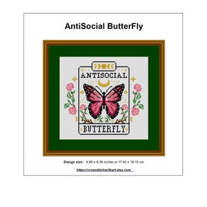 K&ouml;nnte beinhalten: Gerahmte Kreuzstichkunst mit dem Text "AntiSocial ButterFly". Das Design zeigt einen rosa Schmetterling, umgeben von floralen Elementen, und das Wort "ANTISOCIAL" dar&uuml;ber. Die Designgr&ouml;&szlig;e betr&auml;gt 17,42 x 16,15 cm.