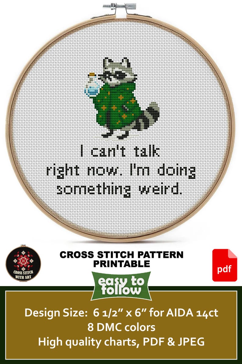 May include: Cross-stitch pattern in a wooden hoop featuring a raccoon wearing a green coat and holding a potion. The text reads, "I can't talk right now. I'm doing something weird." The design size is 6.5" x 6".