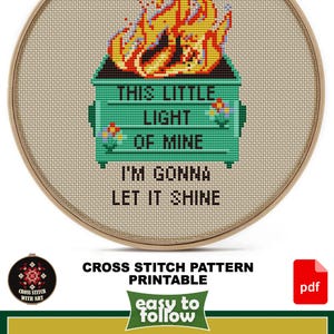 May include: Cross-stitch pattern featuring a green dumpster engulfed in flames, with the text "THIS LITTLE LIGHT OF MINE I'M GONNA LET IT SHINE." The design is in a wooden hoop. The design size is 5" x 7".