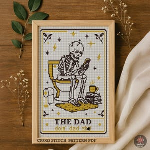 Könnte beinhalten: Ein gerahmtes Kreuzstichmuster mit einem Skelett auf einer Toilette, das auf ein Telefon schaut. Das Design verwendet Schwarz, Weiß und Gold. Der Text unten lautet "THE DAD doin' dad sh*t". Der Text "CROSS STITCH PATTERN PDF" ist ebenfalls sichtbar.