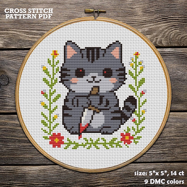 Op de afbeelding: Kruissteekpatroon PDF met een grijze kat met een mes, omringd door bloemmotieven. De kat heeft rode ogen en roze wangen. Het ontwerp is omlijst in een houten hoepel. De tekst "CROSS STITCH PATTERN PDF" staat bovenaan.