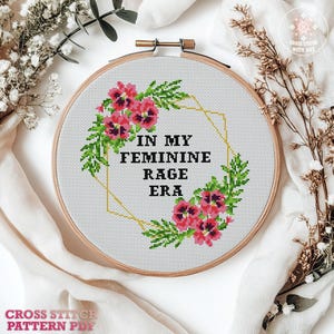 A cross stitch pattern featuring a floral wreath with pink flowers and green leaves. The wreath surrounds the text "In My Feminine Rage Era".
Cross stitch pattern featuring a floral design with the text "In My Feminine Rage Era". The pattern is 8 inches by 8 inches and is designed for 14 count Aida cloth. It uses 8 DMC colors and includes high quality charts in PDF and JPEG formats.
