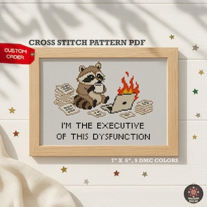May include: A cross stitch pattern PDF featuring a raccoon holding a mug next to a burning laptop and stacks of paper. The text reads I'M THE EXECUTIVE OF THIS DYSFUNCTION. The design is displayed in a wooden frame with 7 inches by 6 inches dimensions.
