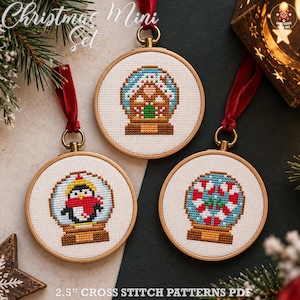 Op de afbeelding: Drie ronde houten borduurringen met kruissteekpatronen van een peperkoekhuisje, een pinguïn en zuurstokken in sneeuwbollen. Elke ring is voorzien van een rood fluwelen lint om op te hangen en de tekst Christmas Mini Set.