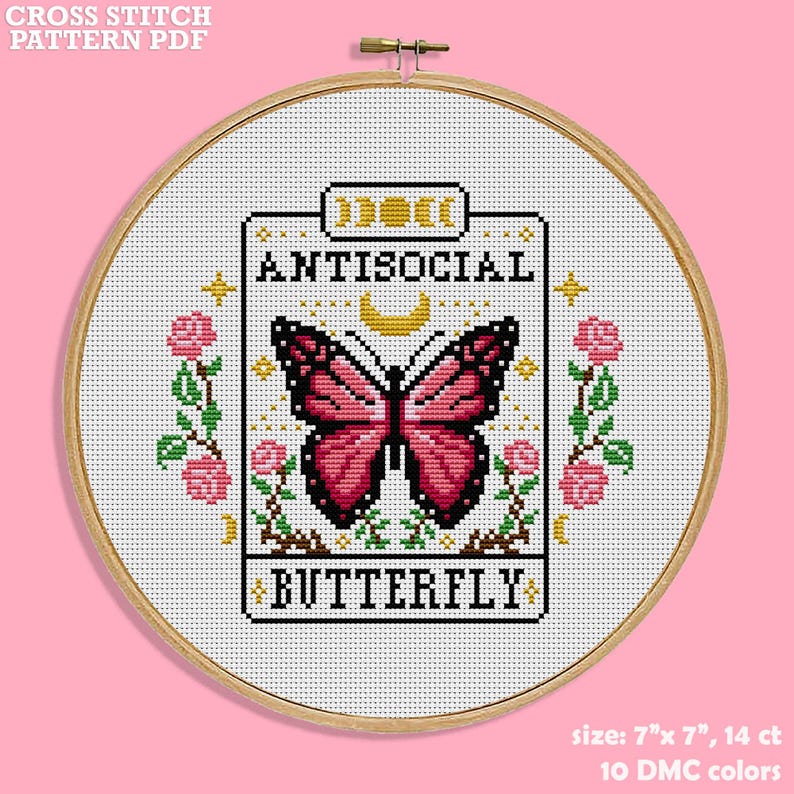 Cross stitch pattern for a butterfly with the text "ANTISOCIAL BUTTERFLY" in a white frame with pink flowers, Tarot card inspired. The pattern is 7 inches by 7 inches and uses 14 count fabric with 10 DMC colors.