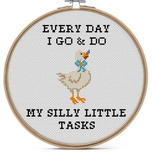 May include: A circular wooden embroidery hoop containing white fabric with a cross-stitch design of a white goose with an orange beak and feet, wearing a blue bow tie. The black text reads: EVERY DAY I GO & DO MY SILLY LITTLE TASKS.