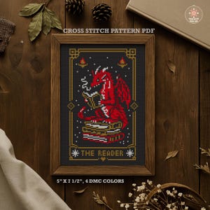 May include: Cross stitch pattern PDF featuring a red dragon reading a book, with the text "THE READER". The design is framed in a wooden border. The dimensions are 5" x 7 1/2" and uses 4 DMC colors.