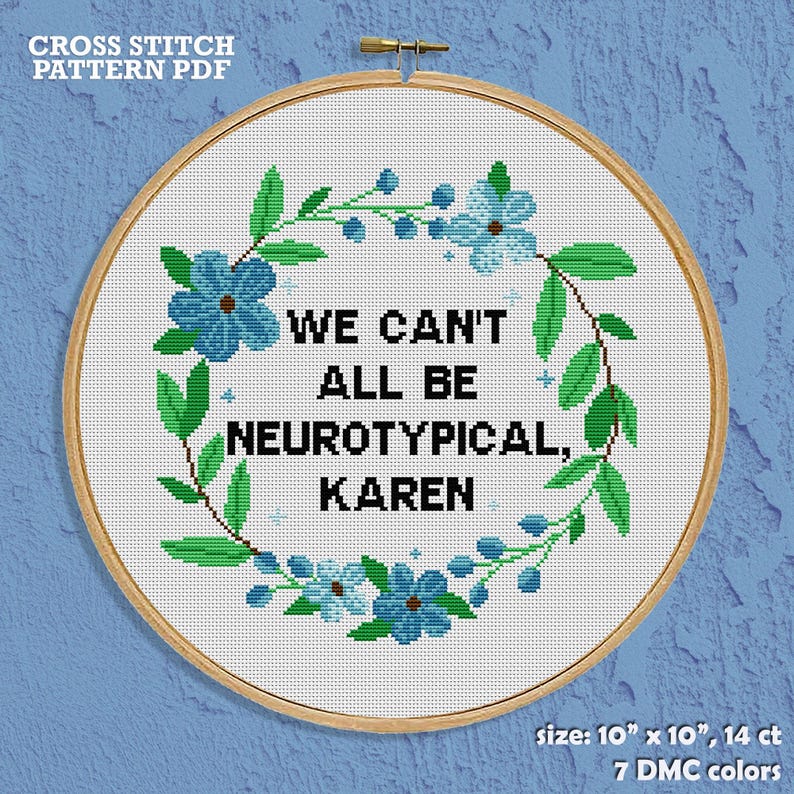 May include: Cross-stitch pattern in a wooden hoop. The design features the text "WE CAN'T ALL BE NEUROTYPICAL, KAREN" surrounded by a wreath of blue flowers and green leaves. The pattern size is 25.4 cm x 25.4 cm.